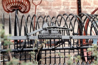 This item formed part of a display in the small museum of rural life near Brodick, on the island of Arran. The picture was taken in the early 1980's and shows a horsedrawn implement, possibly a hay rake, manufactured in Maybole.  Click on the image to view full size.